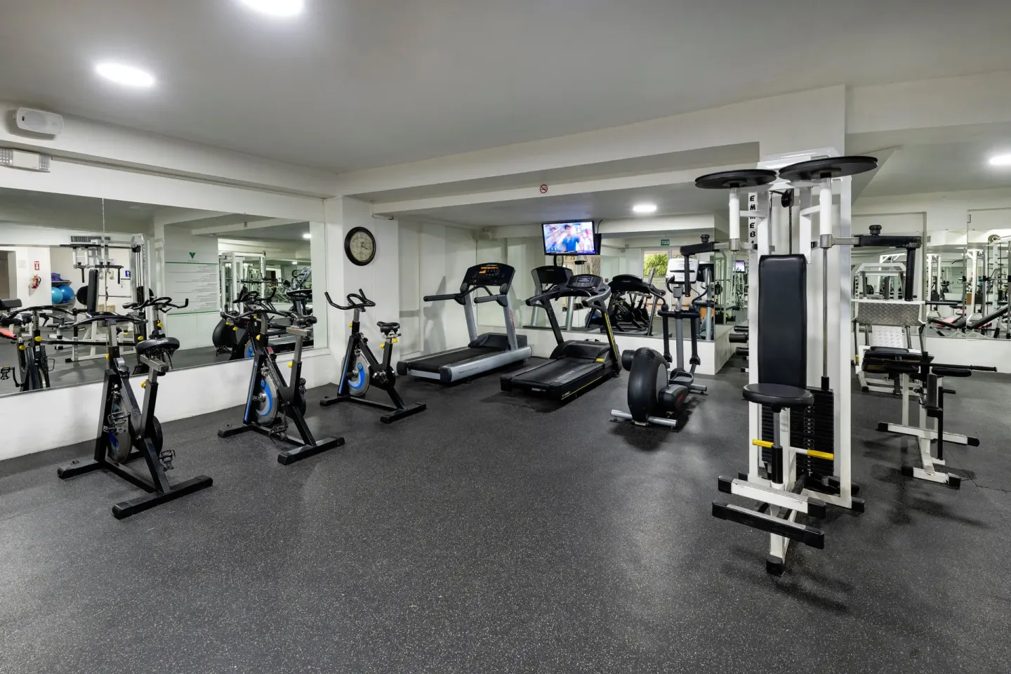 Fitness room with treadmills, bikes, weight machines, and mirrors at Viva Heavens.