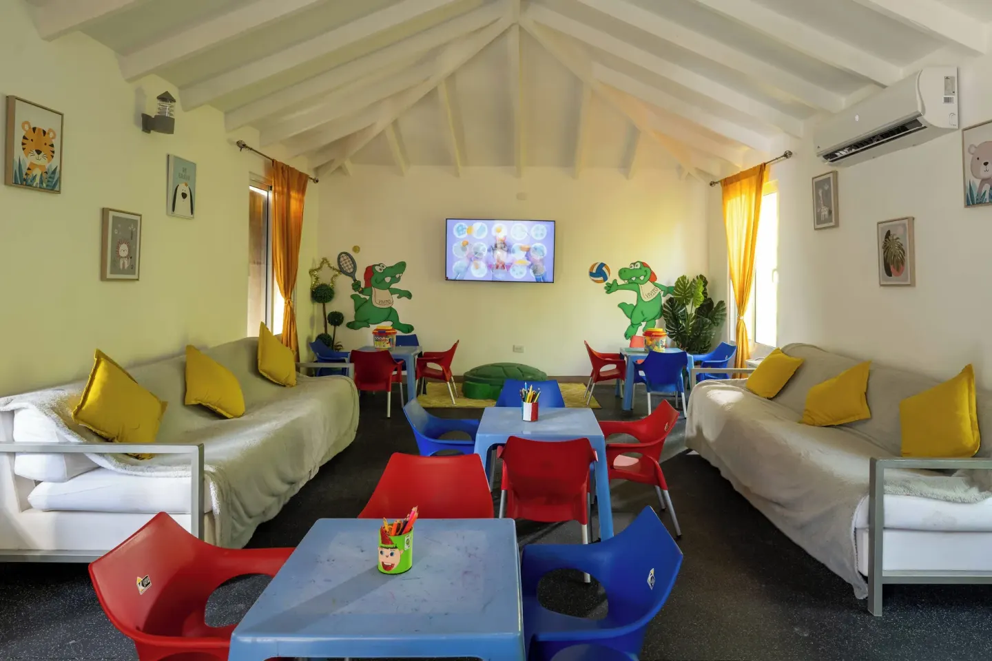 Kids club playroom with small tables, colorful chairs, and sofas at Viva Heavens.