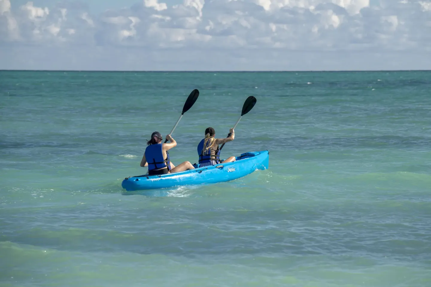 Two guests kayaking on turquoise ocean water at Viva Heavens.