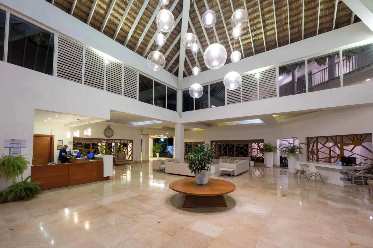 Open lobby with reception desks, seating, and high thatched ceiling at Viva Heavens.