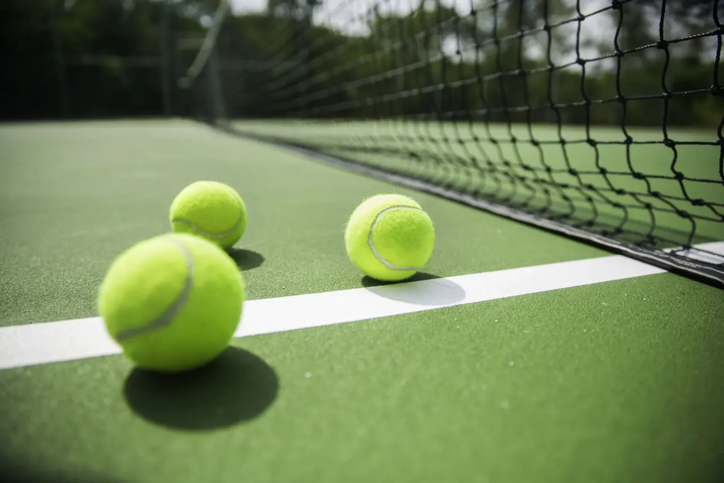 Tennis balls on a green court beside the net at Viva Heavens.