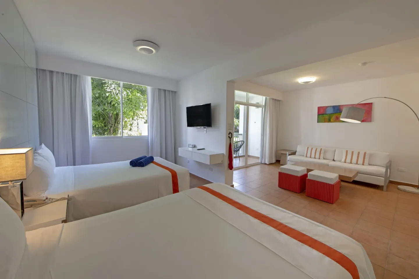 Amnesia room with two beds, sofa, wall TV, and balcony doorway at Viva Heavens.