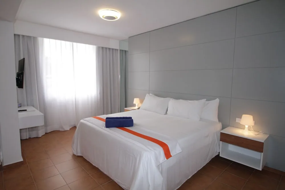 Nirvana Room king bed with white linens and window at Viva Heavens.