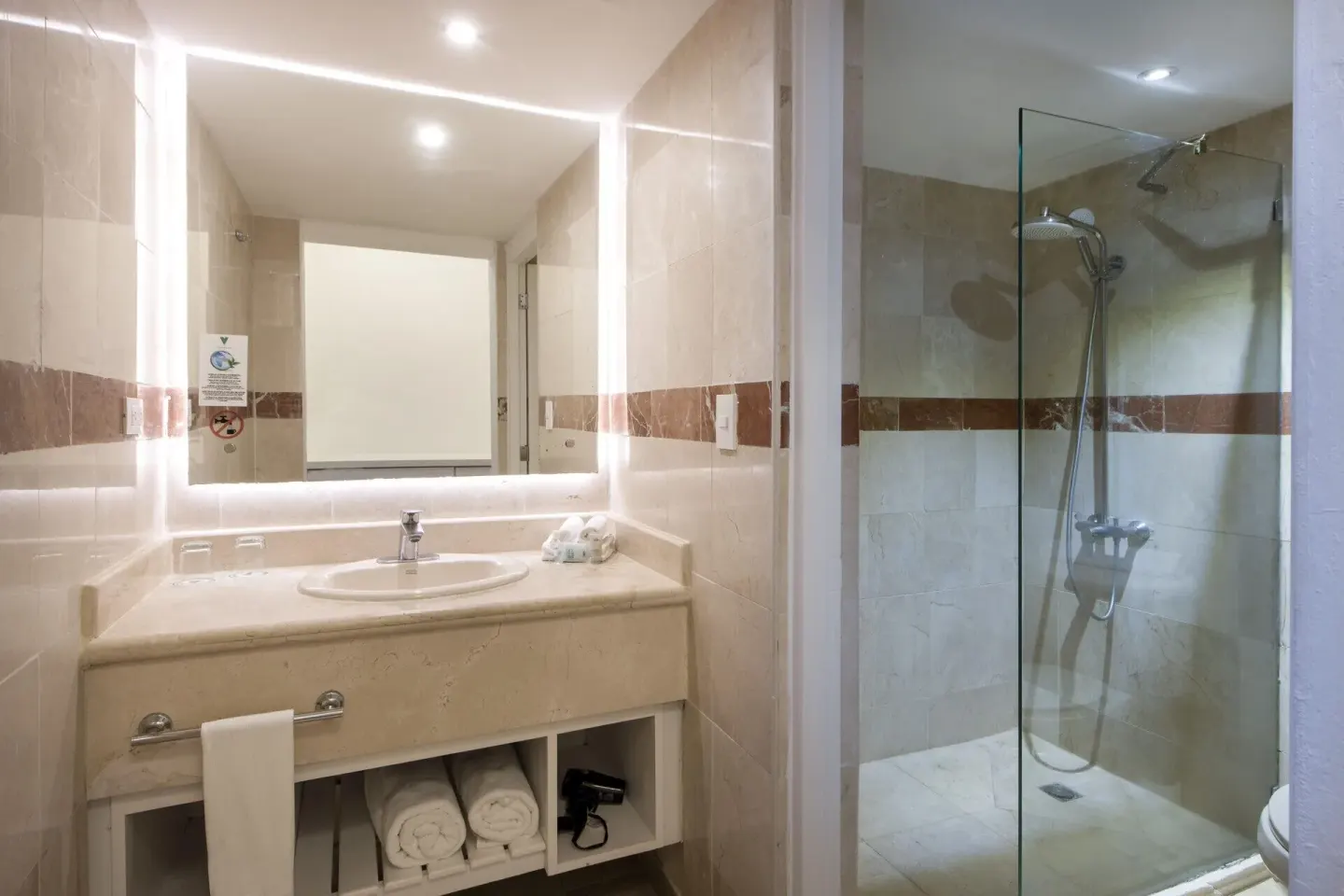 Superior Nirvana Room bathroom showing lit mirror, sink vanity and glass shower at Viva Heavens.