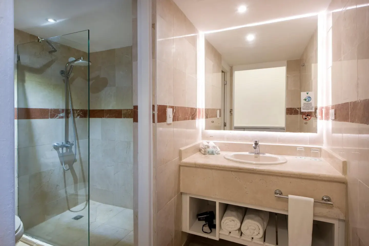 Superior Nirvana Room bathroom with glass shower, vanity and illuminated mirror at Viva Heavens.