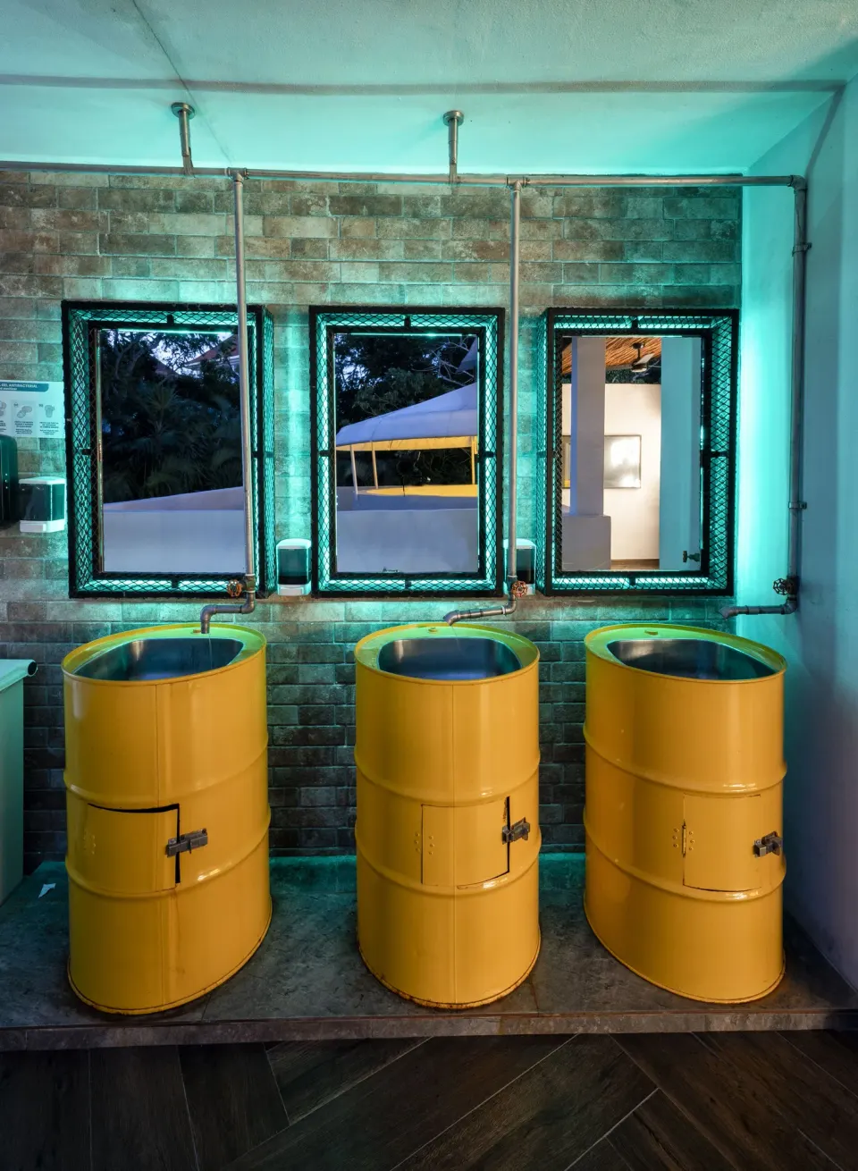 Three yellow barrel-style sinks in a restroom at Viva Maya