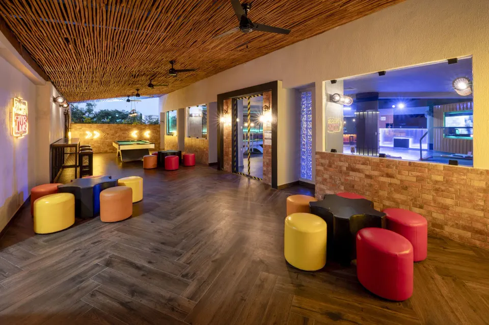 Open games lounge with stools and poufs under a woven ceiling at Viva Maya