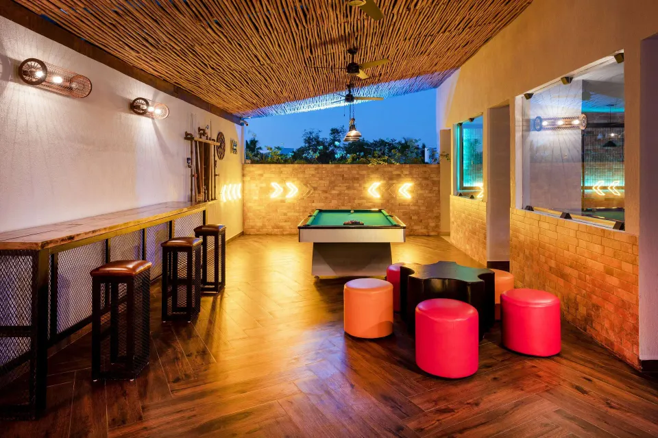 Indoor games area with a pool table and colorful stools at Viva Maya
