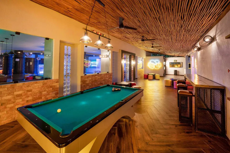 Pool table in a long games lounge with neon accents at Viva Maya