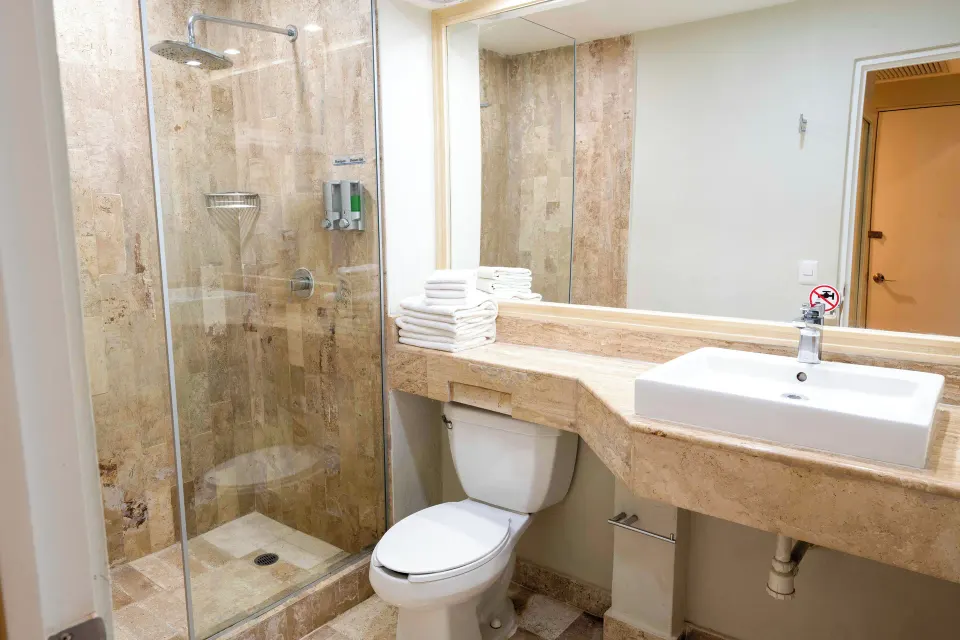 Guest bathroom with glass shower, stacked towels, and single sink at Viva Maya.