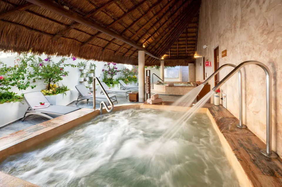 Close-up of a heated spa pool with water jets and loungers under a palapa at Viva Maya.
