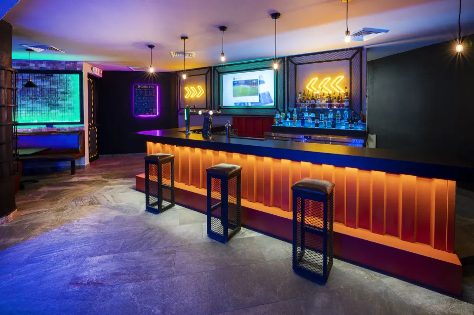 Intimate bar counter with three high stools and warm accent lighting at Viva Maya.