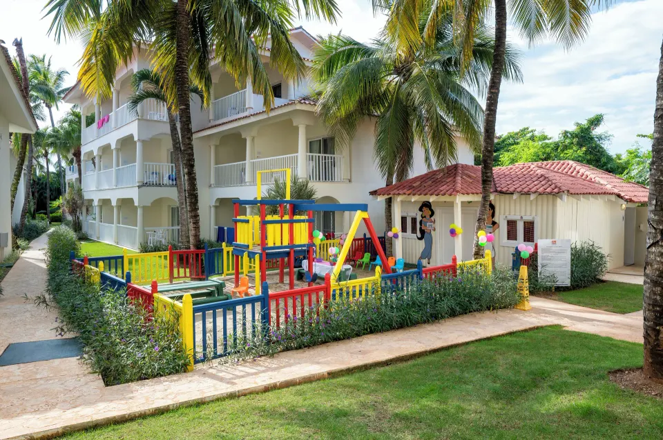 Colorful fenced children's playground near guest buildings at Viva Maya