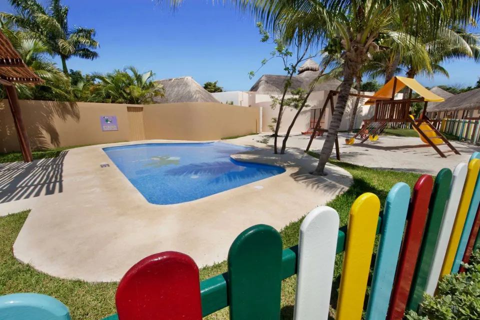Children's pool and playground area fenced with colorful pickets at Viva Maya.
