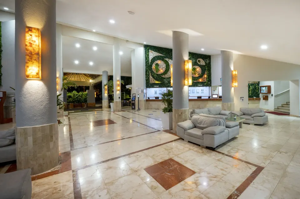 Wide-angle view of Viva Maya's lobby with tiled floor, sofas and decorative mosaic behind reception.