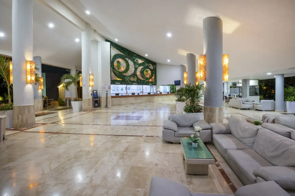 Lobby reception area at Viva Maya with check-in desk beneath a large decorative wall mosaic.