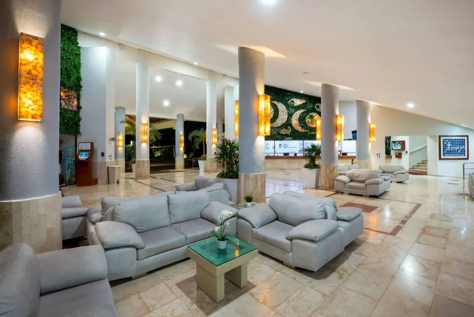 Bright open lobby seating area at Viva Maya with pale sofas and tiled floors.
