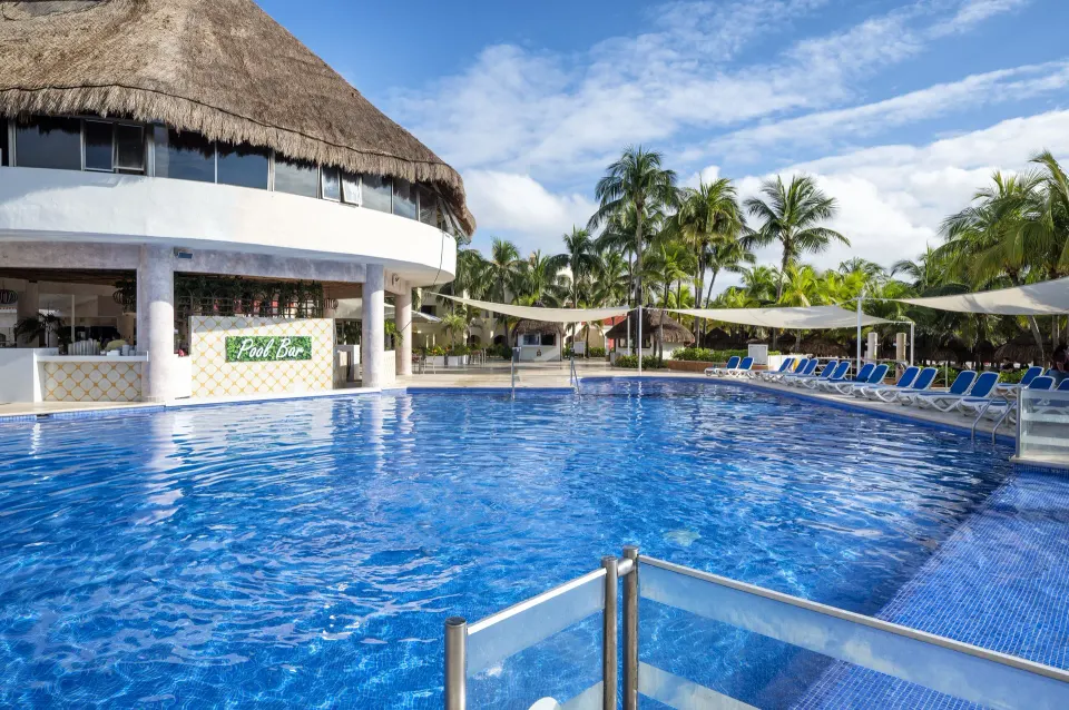 Wide view of the pool and round thatched pool bar with lounge chairs at Viva Maya.