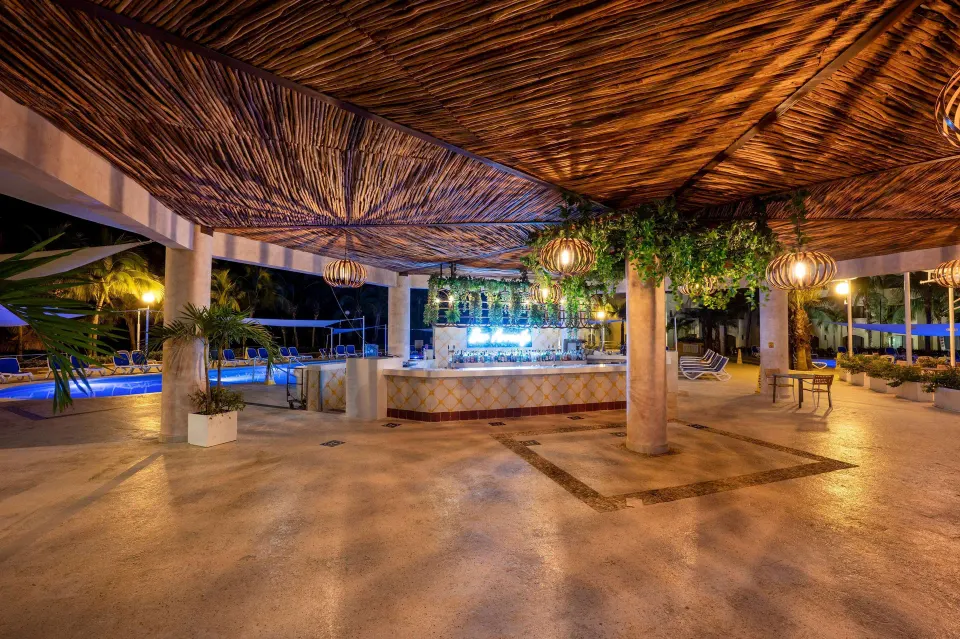 Open-air pool bar with thatched ceiling and hanging greenery at Viva Maya