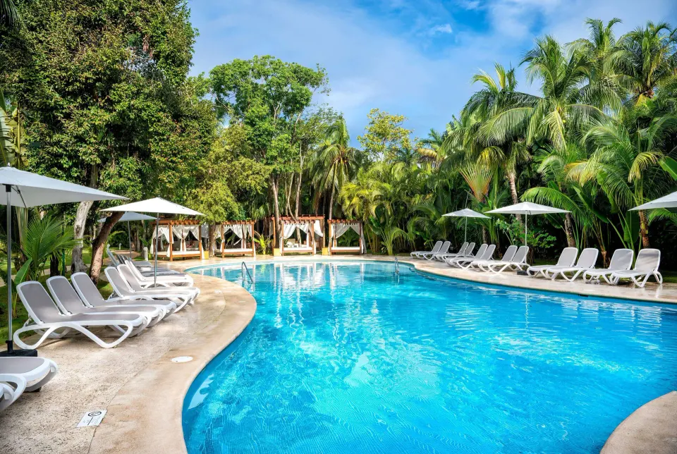 Smaller secluded pool with cabanas and tropical foliage at Viva Maya.