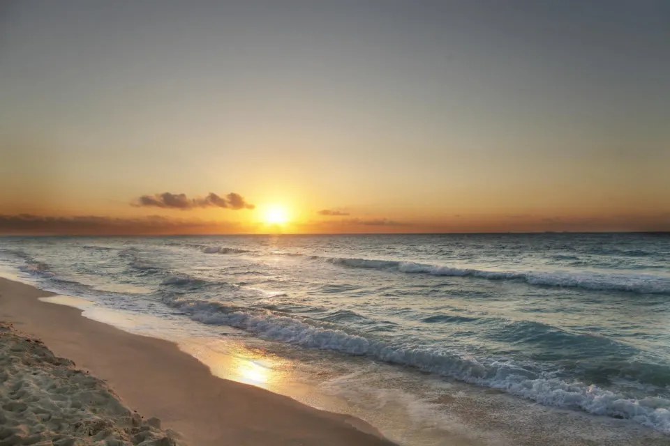 Sunrise over the ocean with gentle waves on the beach at Viva Maya