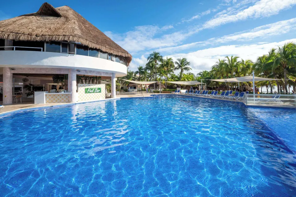 Resort pool with swim-up bar under a thatched palapa at Viva Maya.