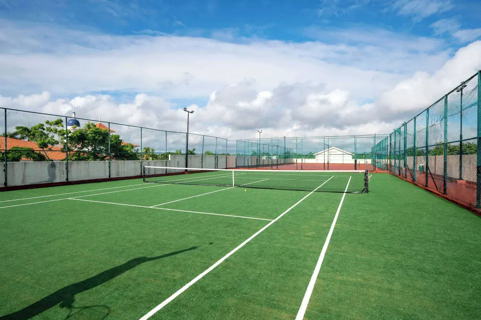 Outdoor tennis court at Viva Maya under a partly cloudy sky