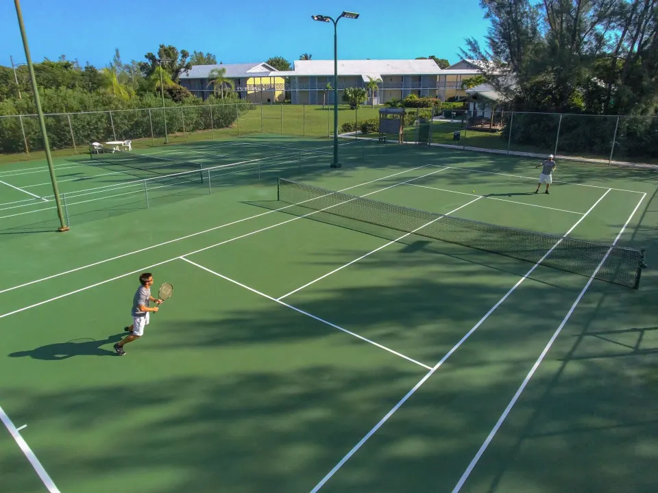 Two guests playing tennis on a resort court at Viva Maya