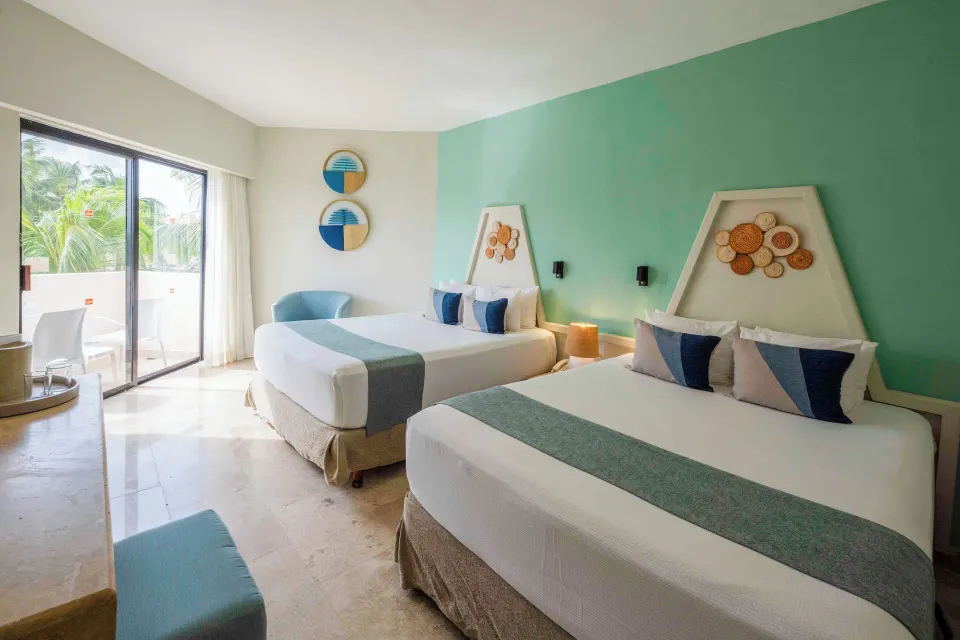 Two queen beds and patio door with tropical plants visible at Viva Maya