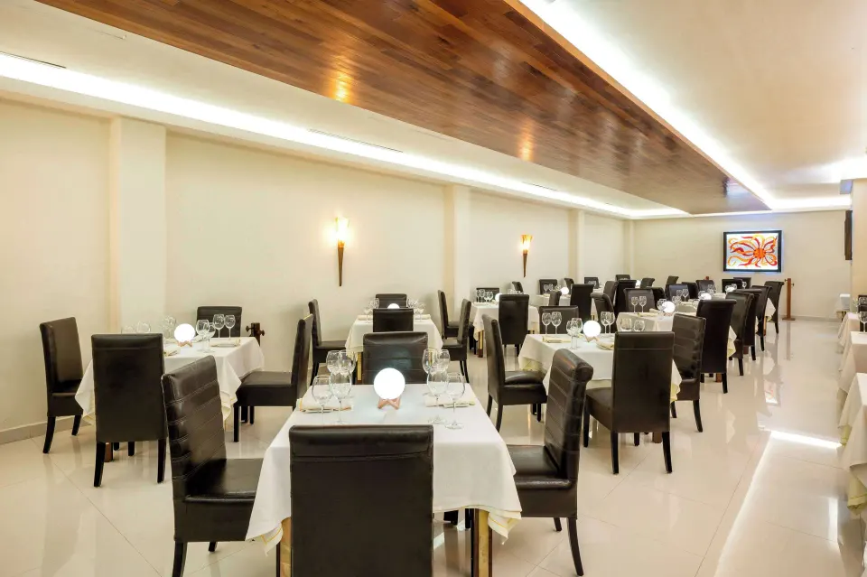 Contemporary dining room with white floors and leather chairs at Viva Maya