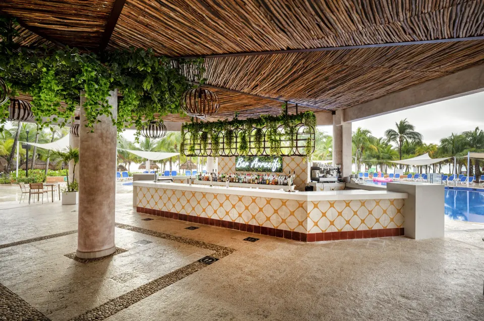 Open-air poolside bar with tiled counter and greenery at Viva Maya.