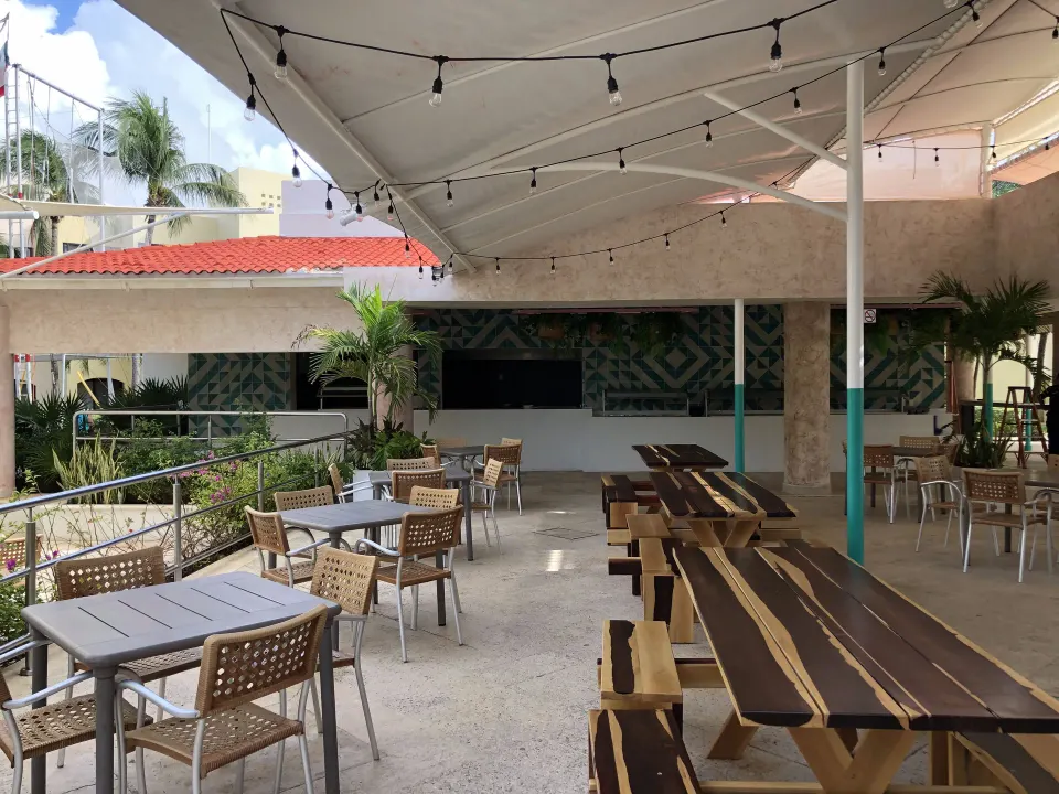 Covered outdoor seating area with picnic tables and string lights at Viva Maya