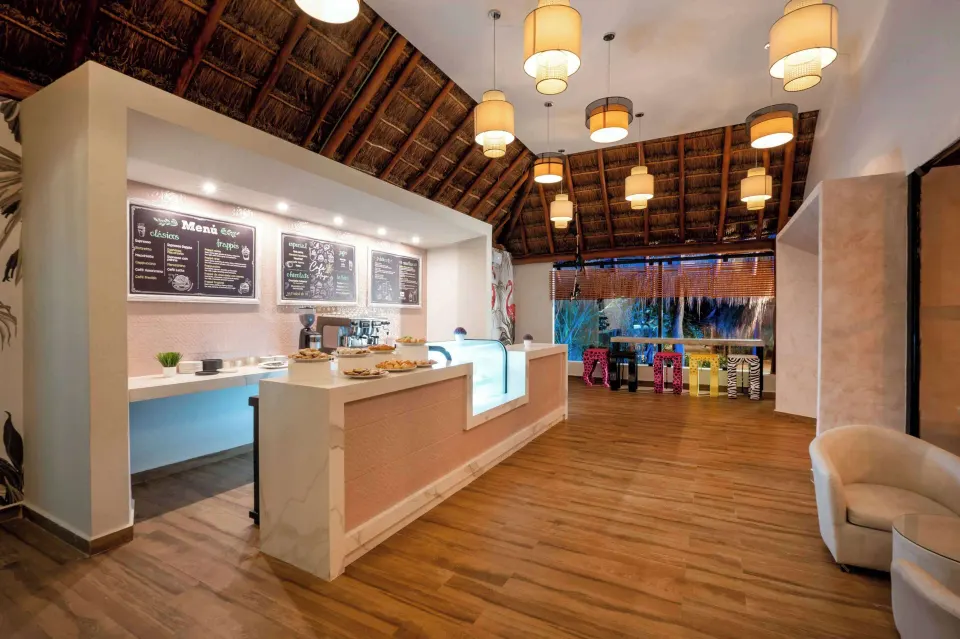 Palapa café counter with menu boards and pastries at Viva Maya