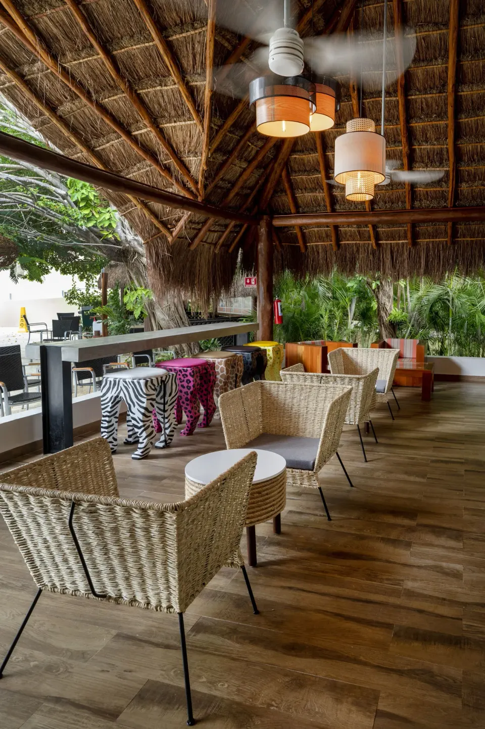 Palapa lounge with wicker seating and pendant lights at Viva Maya
