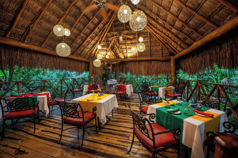 Thatched-roof palapa dining terrace set among lush greenery at Viva Maya