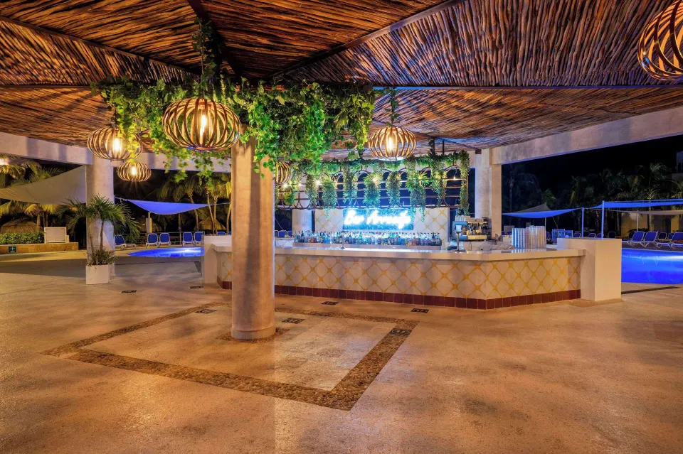 Poolside bar with neon sign and hanging lanterns at Viva Maya