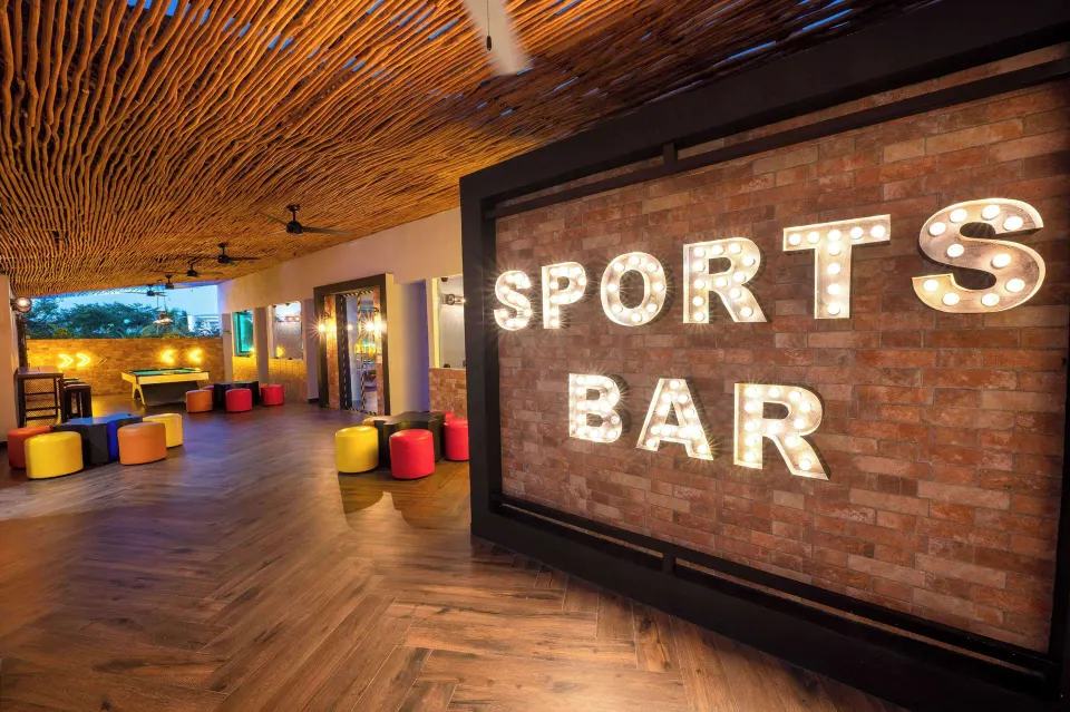 Illuminated 'SPORTS BAR' sign and colorful seating area at Viva Maya