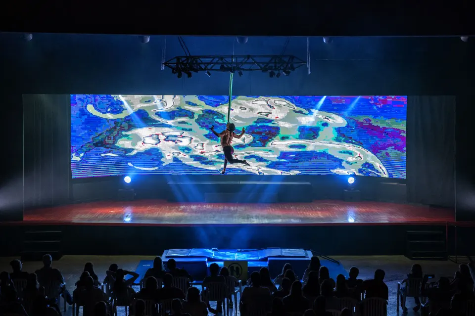 Aerial acrobat suspended above the stage with LED visuals at Viva Maya