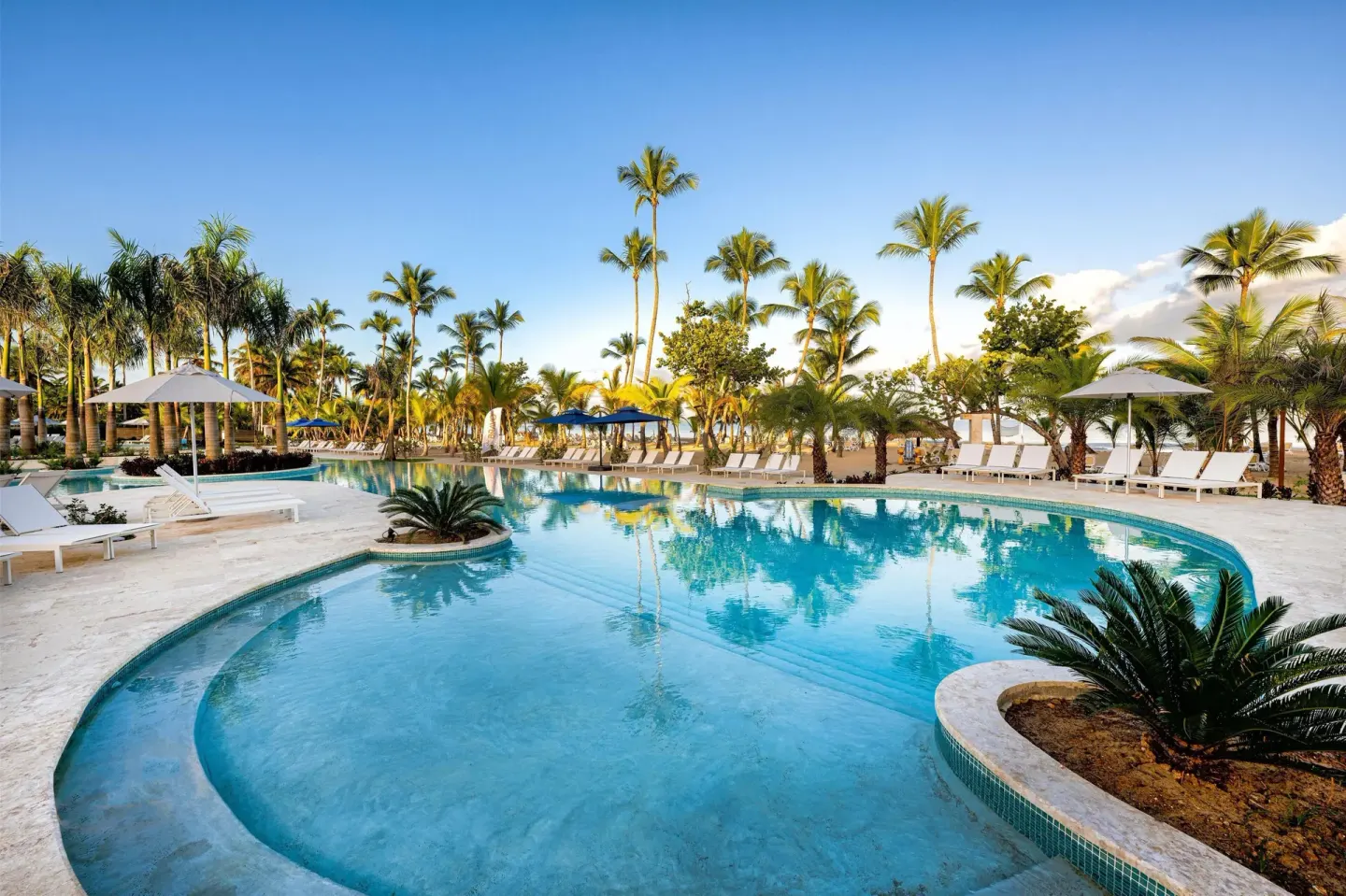 Lagoon-style pool reflecting palm trees beside the beach at Viva Miches.