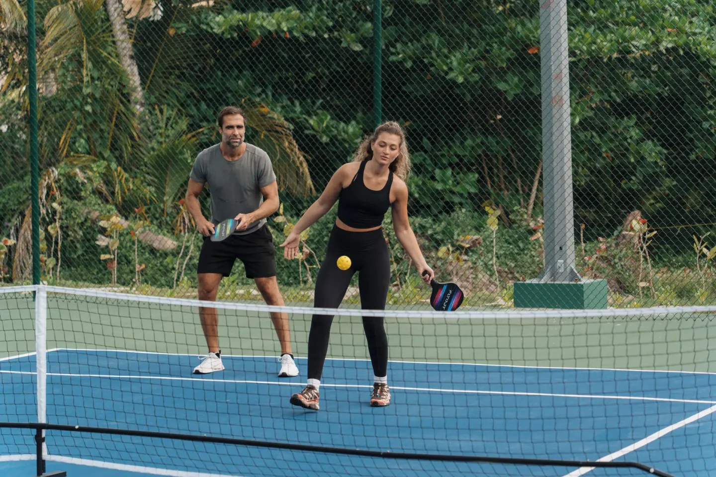 Two guests playing pickleball on an outdoor court at Viva Miches.