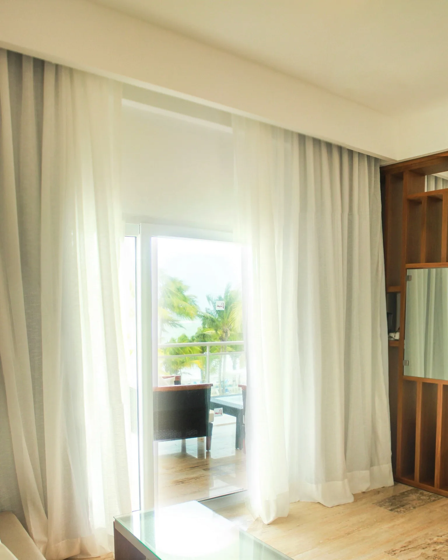 Guest room balcony doorway with sheer curtains at Viva Tangerine.