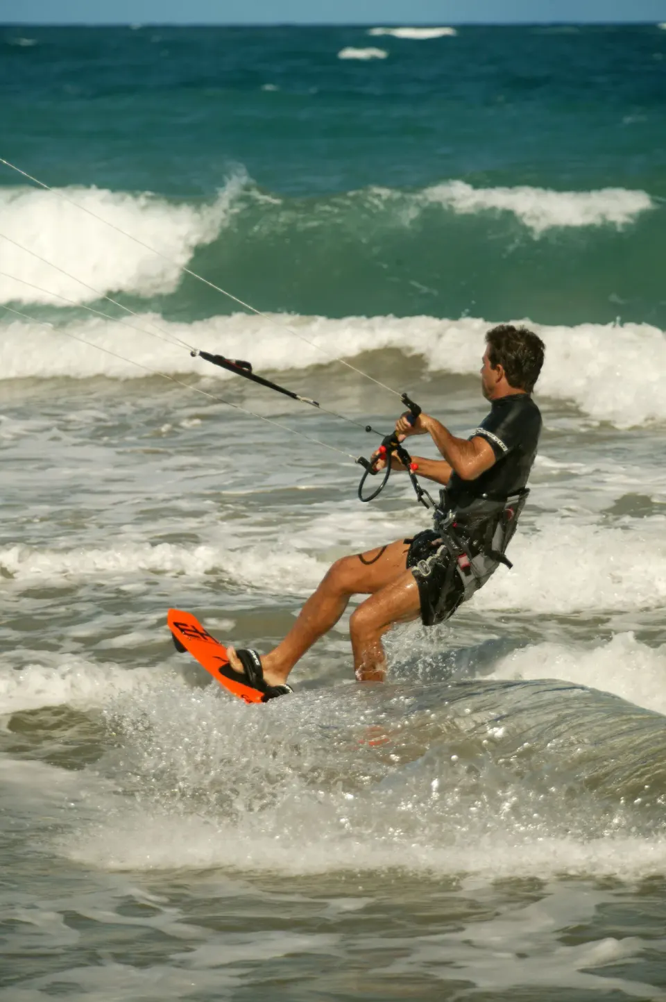 Kitesurfer riding through breaking waves off the beach at Viva Tangerine.