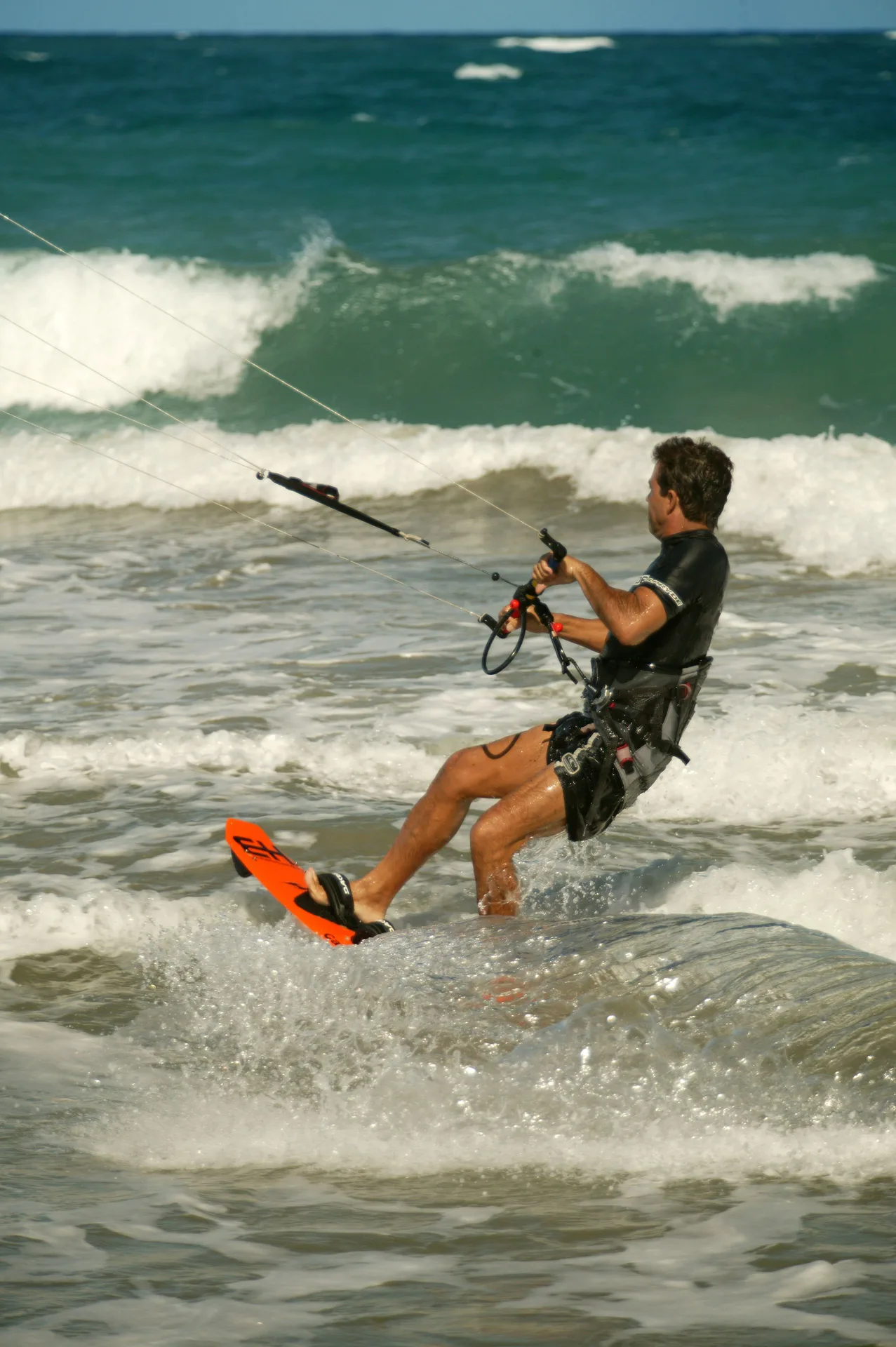 Kitesurfer riding through breaking waves off the beach at Viva Tangerine.