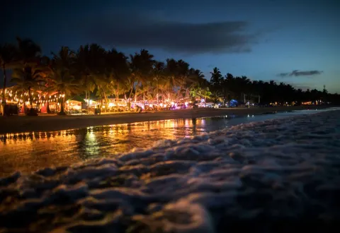 Nighttime beach scene with lights along the shore at Viva Tangerine.