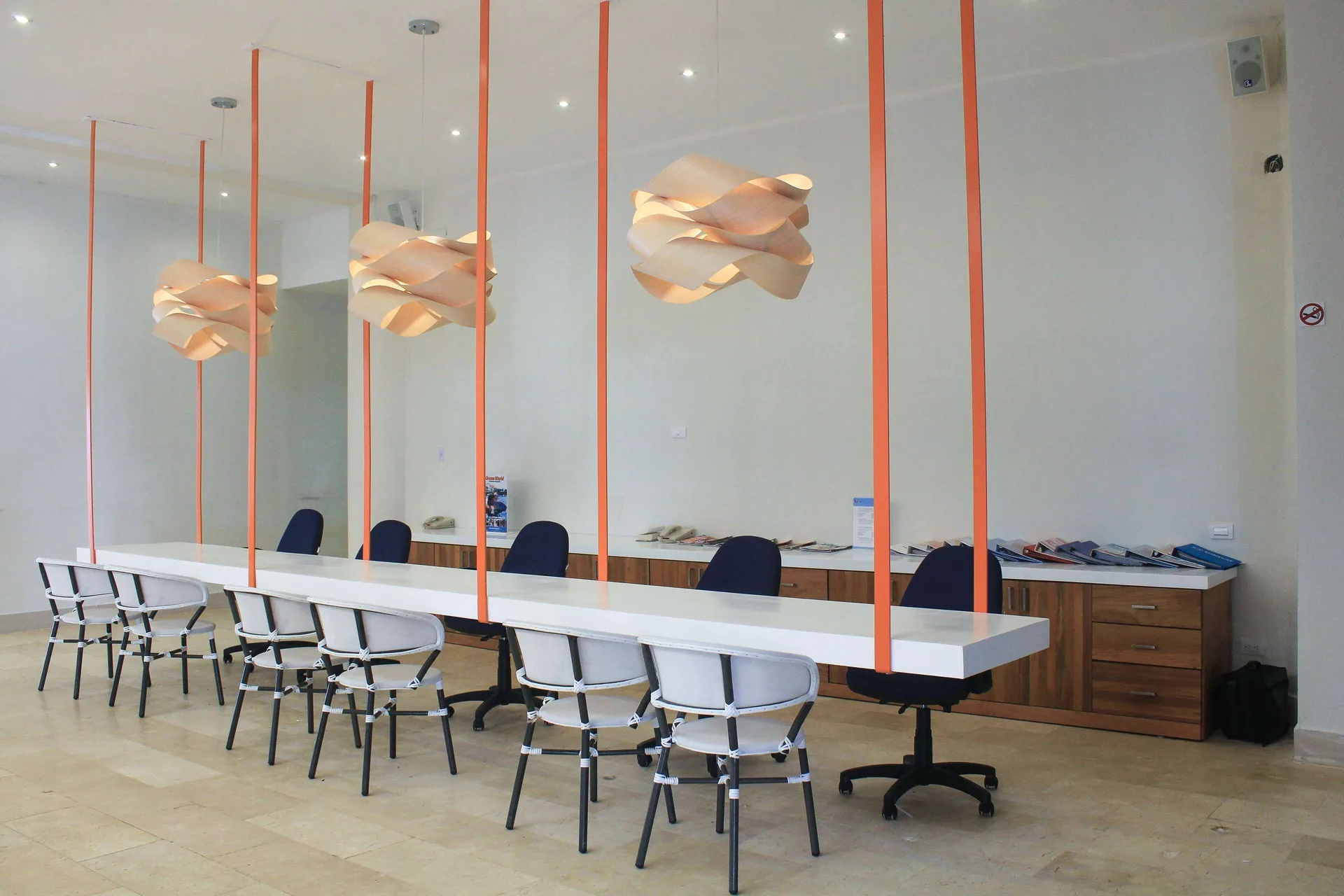 Bright workspace with long white table and pendant lights at Viva Tangerine.