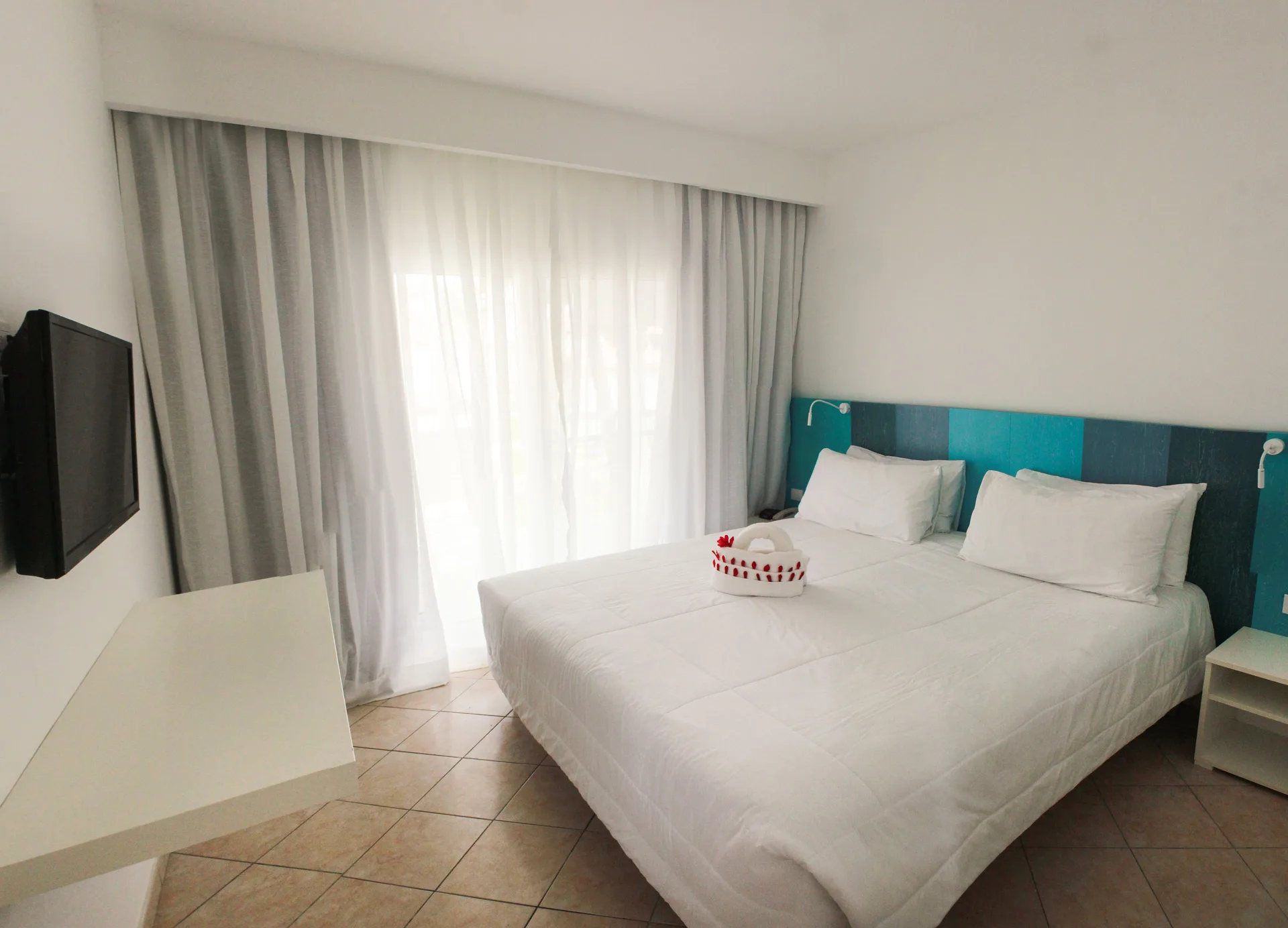 Superior Garden View Room with white bed, TV, and curtains at Viva Tangerine.