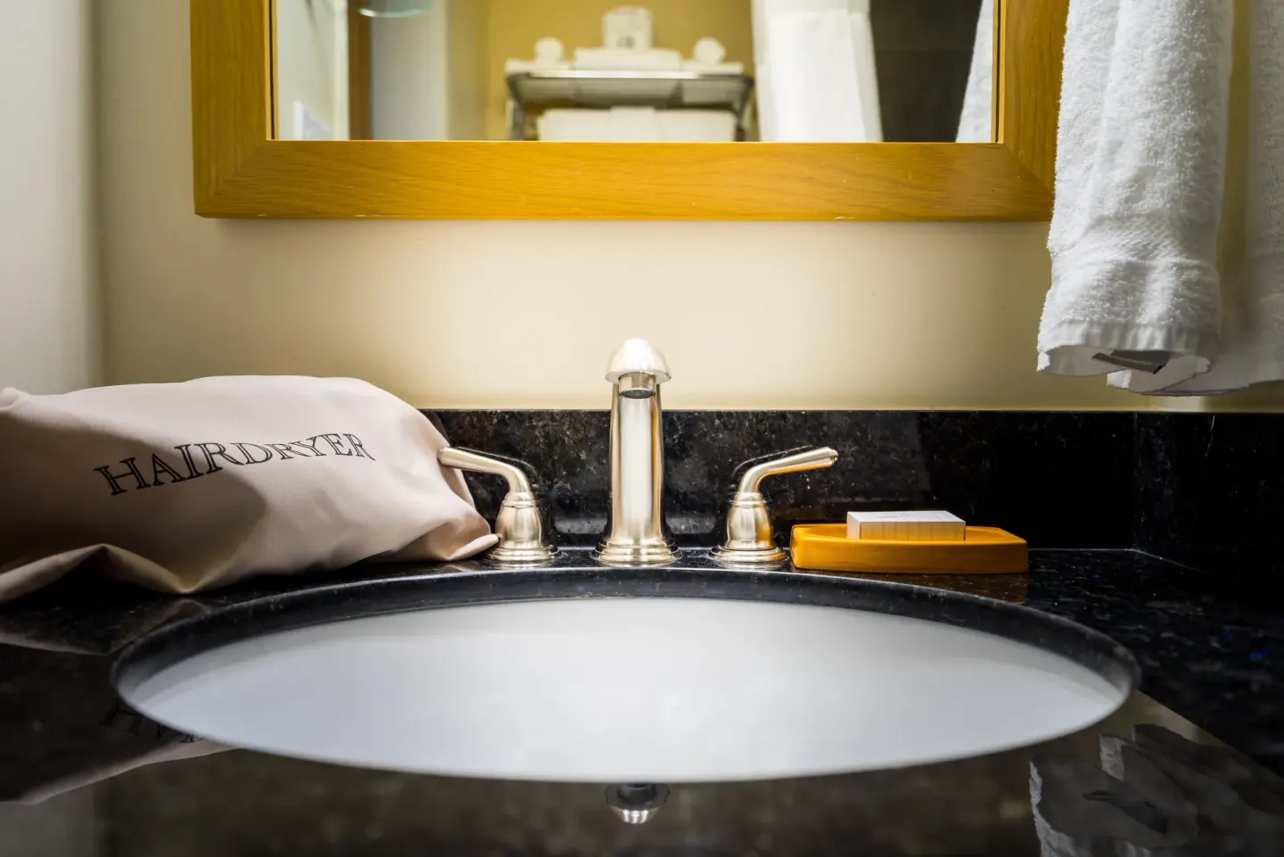 Bathroom sink with hairdryer pouch, towel, and soap dish at Vive Hotel Waikiki.