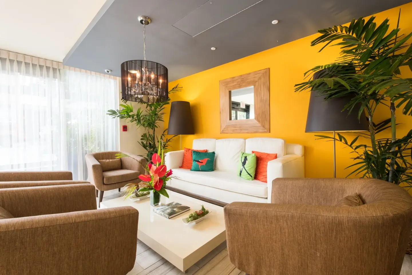 Bright lounge corner with yellow wall and white sofa at Vive Hotel Waikiki.