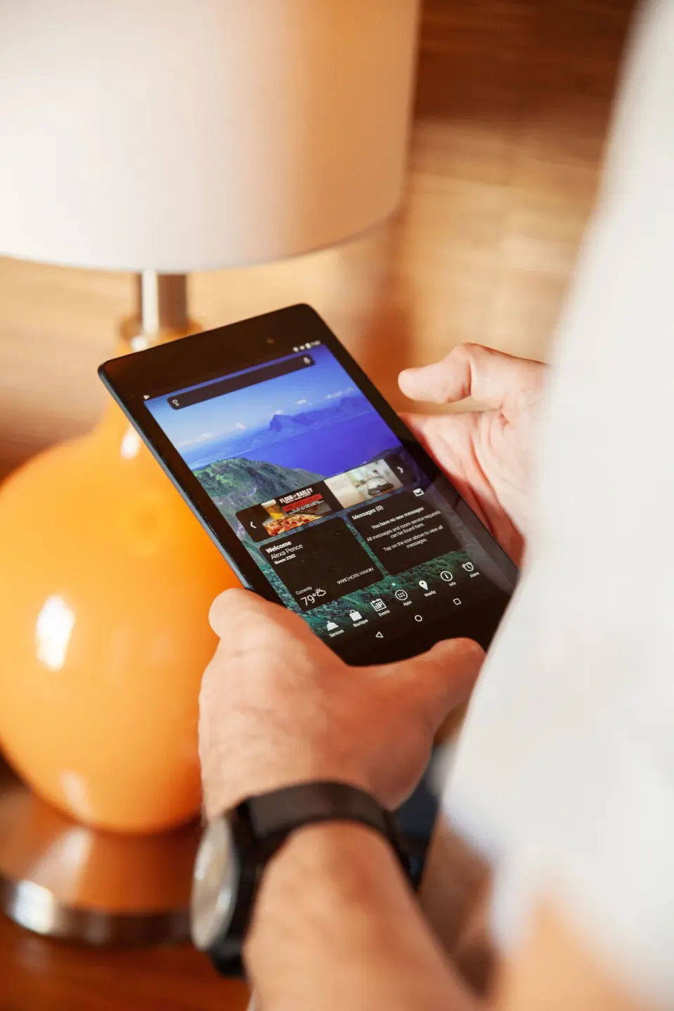 Guest holding an in-room tablet beside a lamp at Vive Hotel Waikiki.