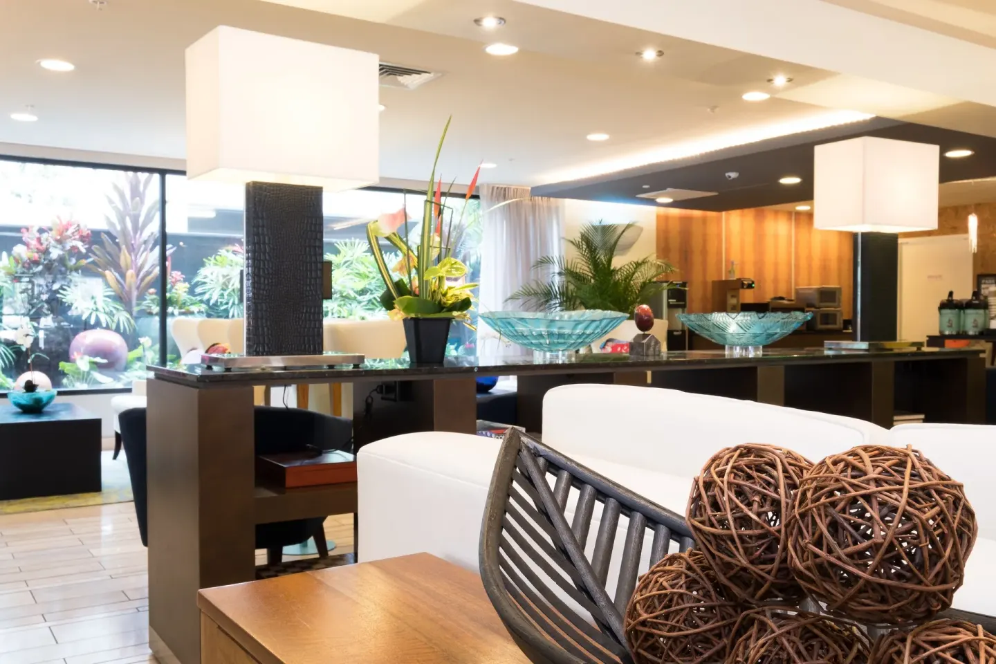 Decorative bowls, lamps, plants, and lounge seating appear in the lobby at Vive Hotel Waikiki.